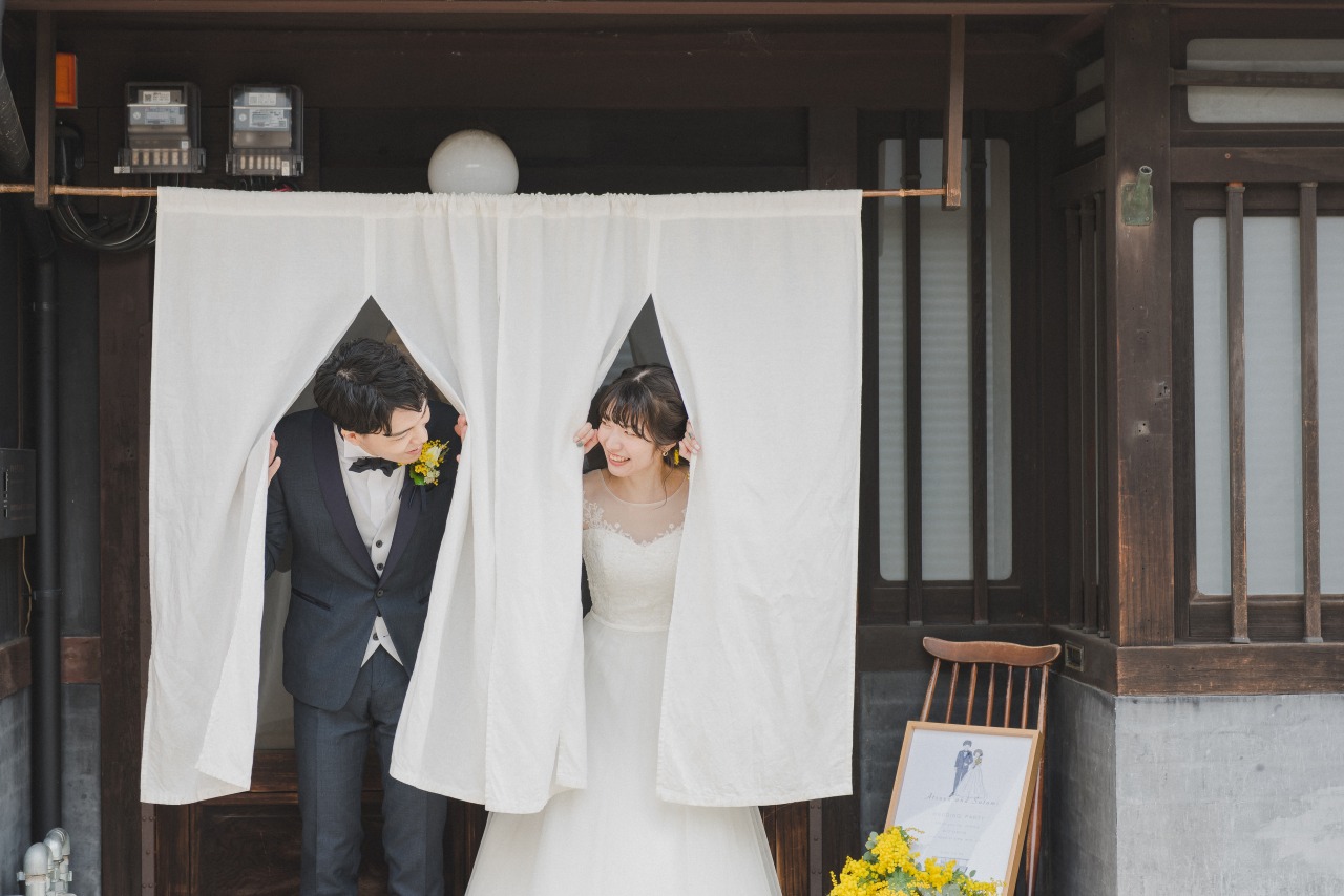 京都の町家で結婚式　のれんをくぐる新郎新婦