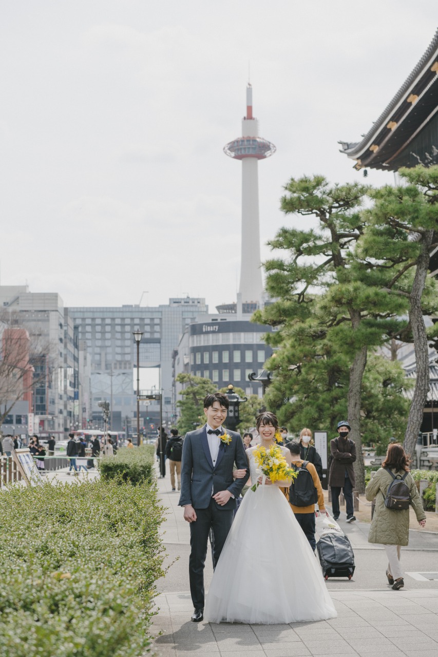 京都タワーを背景に結婚式の撮影をする新郎新婦