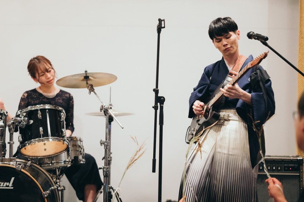 ベースを弾いてる紋付袴姿の新郎